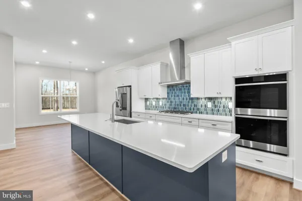 a view of kitchen with kitchen island a sink stainless steel appliances and cabinets