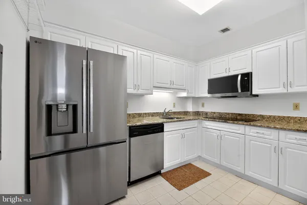 a kitchen with granite countertop white cabinets and stainless steel appliances