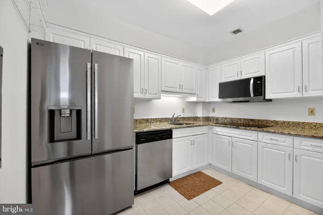 a kitchen with granite countertop white cabinets and stainless steel appliances