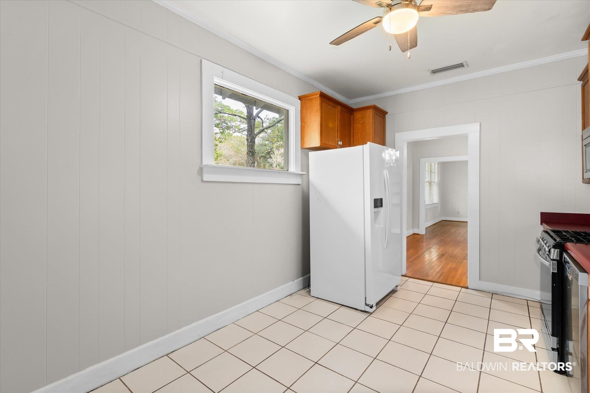 211 3rd Street Mobile, AL 36611 - Photo 8 of 20 Kitchen featuring white refrigerator with ice dispenser, stainless steel range with gas stovetop, light tile patterned floors, crown molding, and ceiling fan