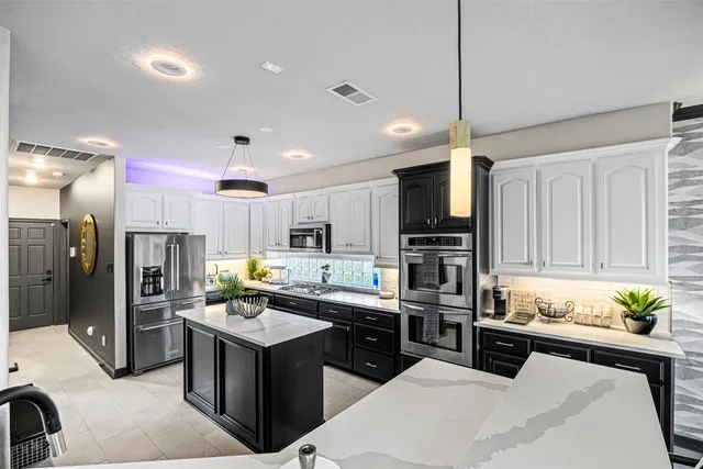 a kitchen with kitchen island granite countertop a refrigerator stove top oven and sink