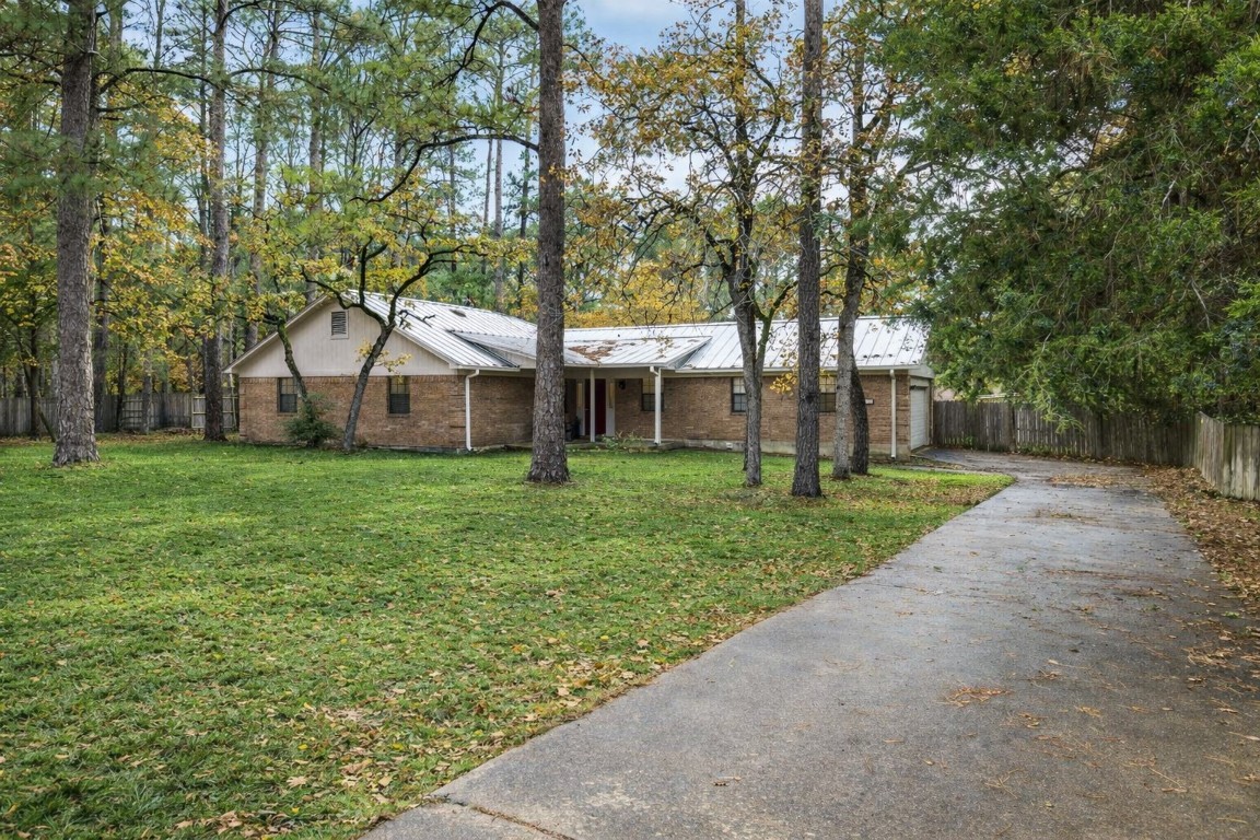 Single story home with driveway, brick siding, a metal roof, and a garage