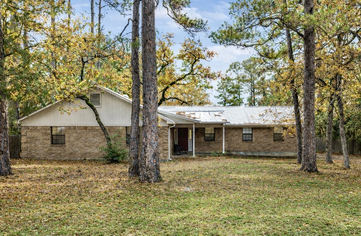326 Pine View Loop Bastrop, TX 78602 - Photo 3 of 29 Back of property featuring brick siding, a yard, and a metal roof