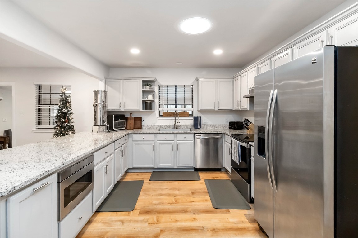 326 Pine View Loop Bastrop, TX 78602 - Photo 10 of 29 Kitchen featuring open shelves, appliances with stainless steel finishes, light stone counters, light wood finished floors, and white cabinets
