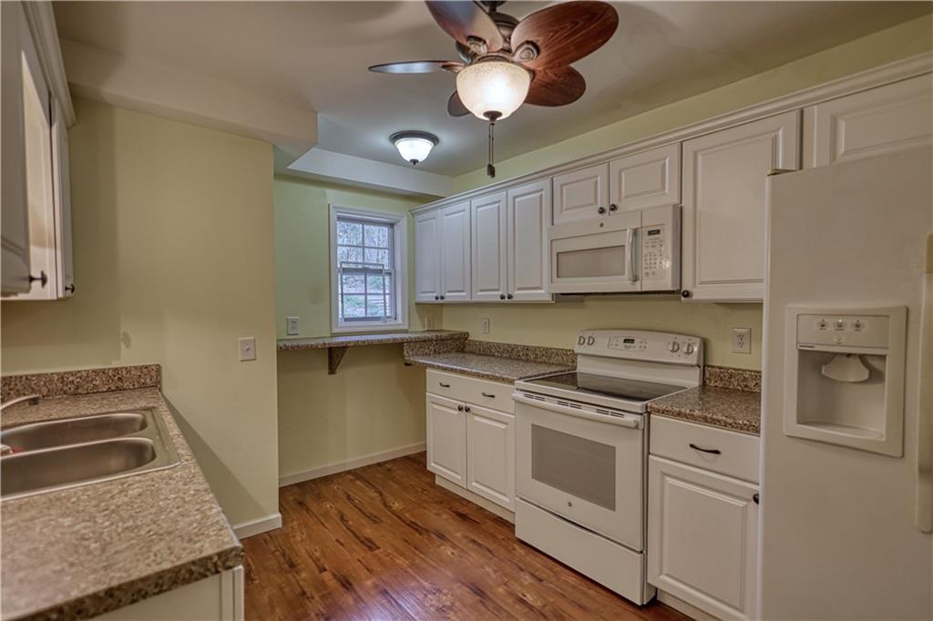 1006 English Oak Lane Winder, GA 30680 - Photo 52 of 83 a kitchen with granite countertop a stove a sink and dishwasher a refrigerator with wooden floor