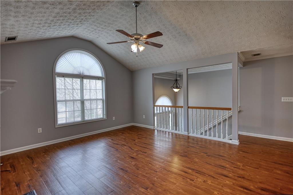 1006 English Oak Lane Winder, GA 30680 - Photo 9 of 83 an empty room with wooden floor chandelier fan and windows