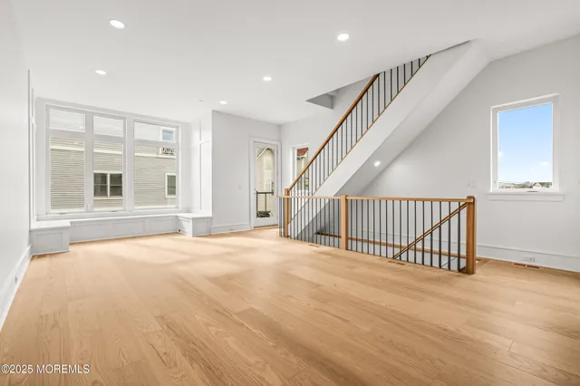 a view of an empty room with wooden floor and stairs