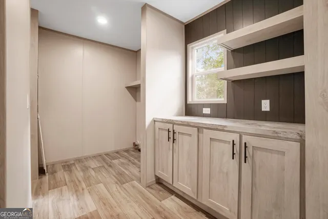 a hallway with white cabinets and wooden floor
