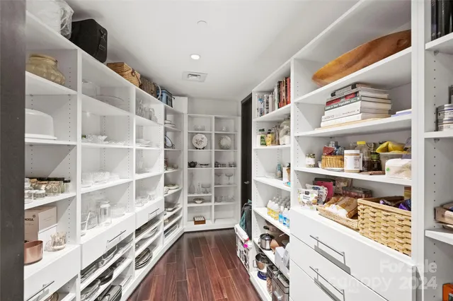 a walk in closet with wooden floor