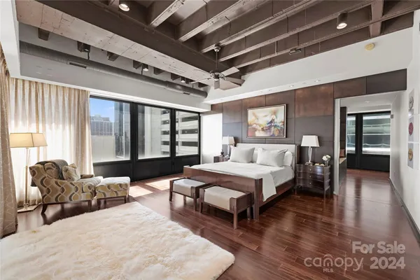 a spacious bedroom with a bed a couch and large window