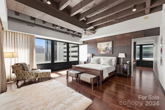 a spacious bedroom with a bed a couch and large window