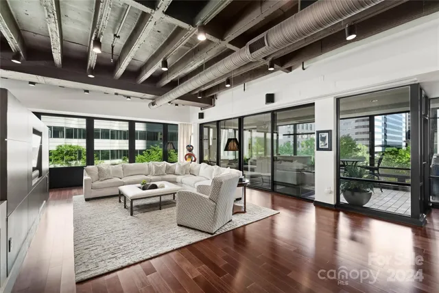 a living room with furniture large windows and wooden floor