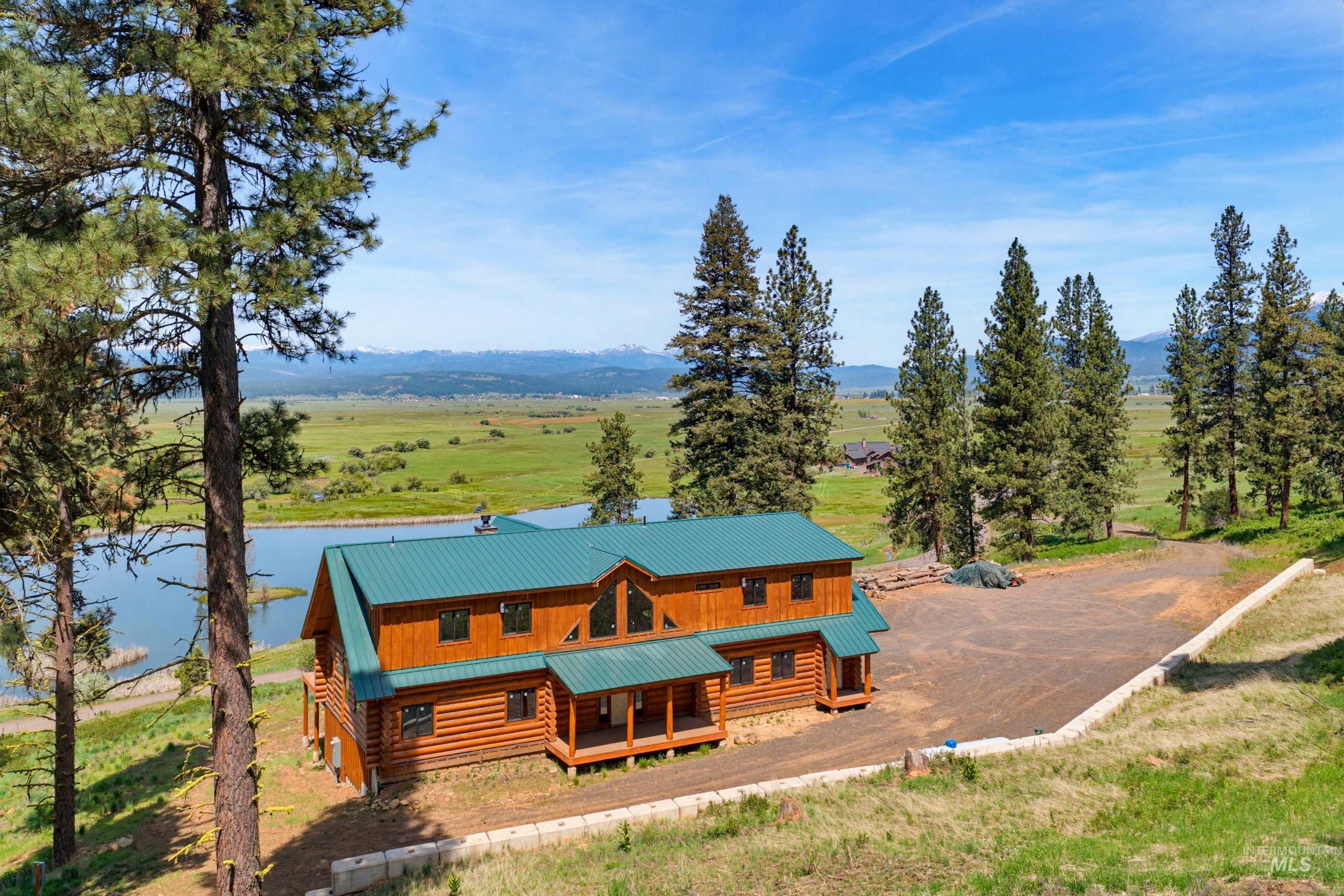 3322 Big Creek Road New Meadows, ID 83654 - Photo 2 of 50 Expansive log cabin residence featuring a prominent green metal roof, multiple windows, and a covered porch