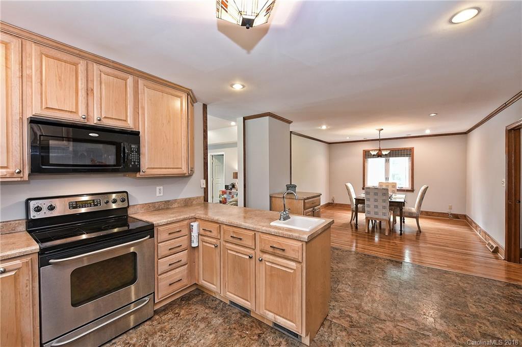 4917 Morgan Mill Road Monroe, NC 28110 - Photo 13 of 36 a open kitchen with stainless steel appliances granite countertop a stove top oven a sink dishwasher a dining table and chairs with wooden floor