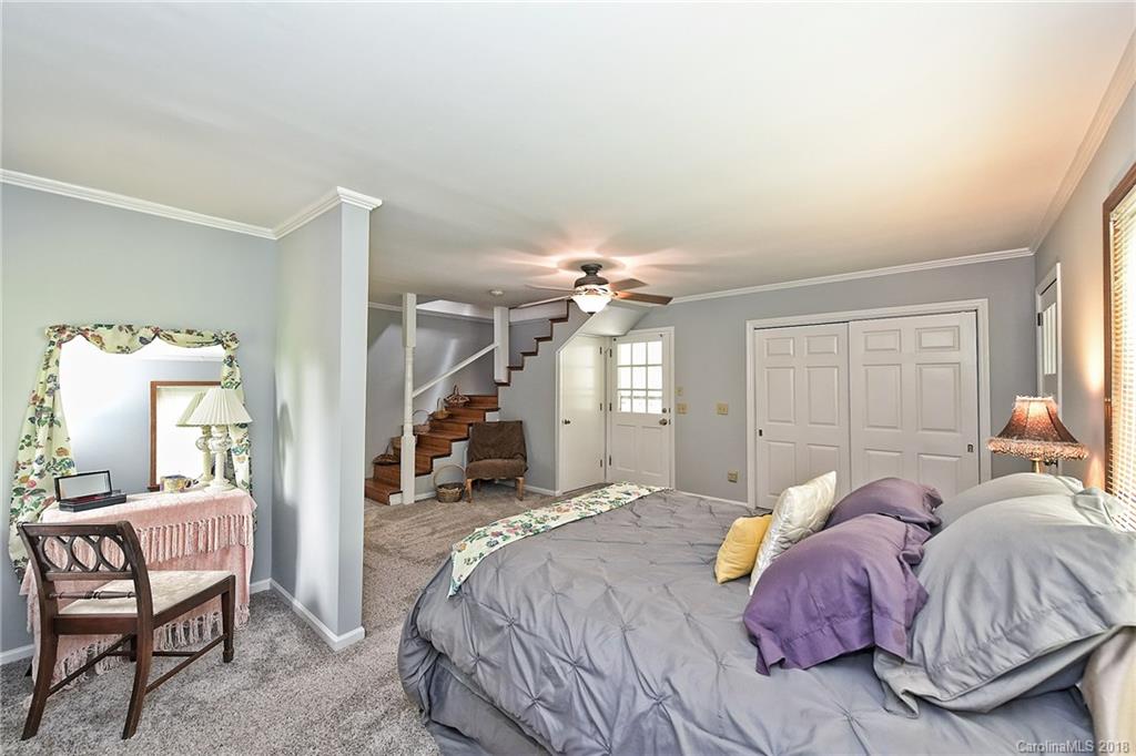 4917 Morgan Mill Road Monroe, NC 28110 - Photo 24 of 36 a spacious bedroom with a bed a chandelier and glass door