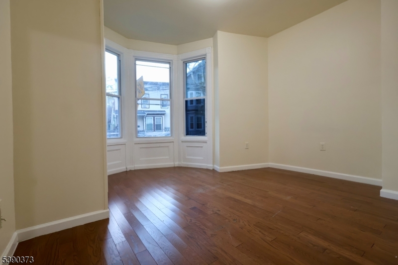 89 Cutler Street, Unit 1 Newark, NJ 07104 - Photo 7 of 13 an empty room with wooden floor and windows