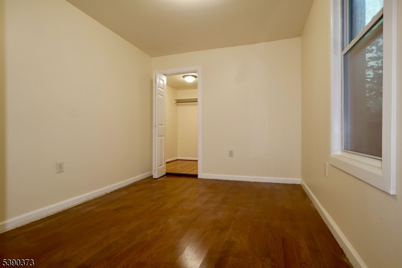89 Cutler Street, Unit 1 Newark, NJ 07104 - Photo 9 of 13 an empty room with wooden floor and windows