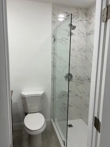 a bathroom with a granite countertop toilet sink and mirror