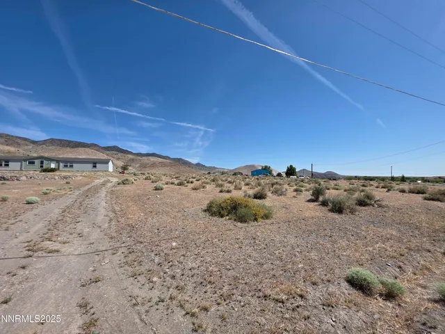 a view of a dry field with mountains in the background