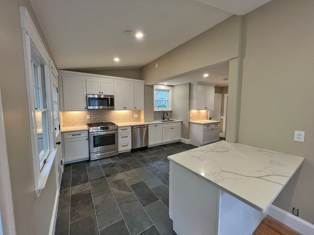 10 Governor Road Arlington, MA 02474 - Photo 10 of 22 a kitchen with a sink a stove a refrigerator and white cabinets