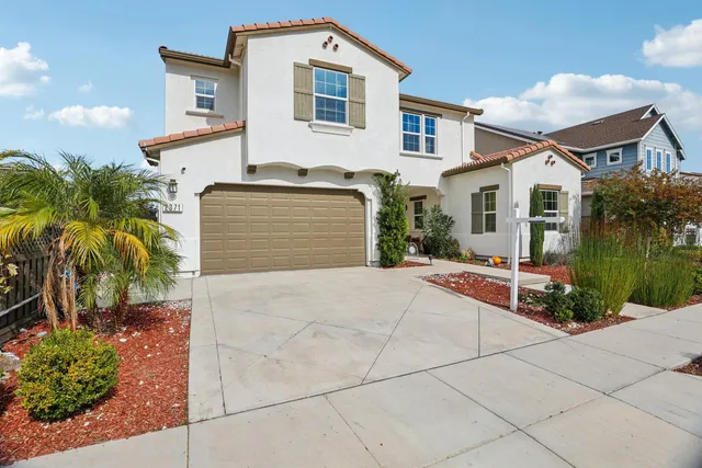a front view of a house with a yard and potted plants
