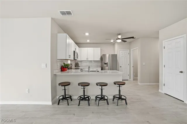 a kitchen with kitchen island a dining table chairs cabinets and stainless steel appliances