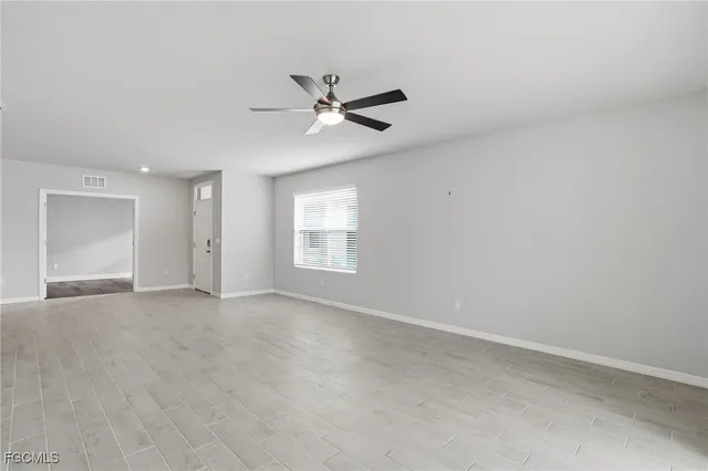 an empty room with windows and fan