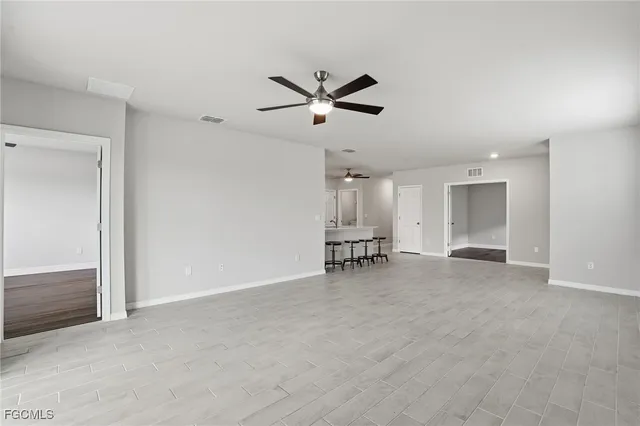 an empty room with chandelier fan and windows
