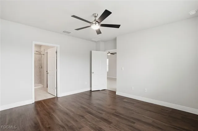 an empty room with wooden floor and a ceiling fan