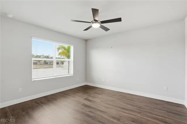 an empty room with wooden floor ceiling fan and windows