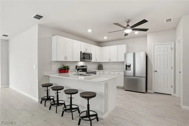 a kitchen with stainless steel appliances a refrigerator a stove a sink dishwasher and white cabinets with wooden floor