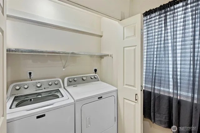 a view of washer and dryer with bathroom in the background