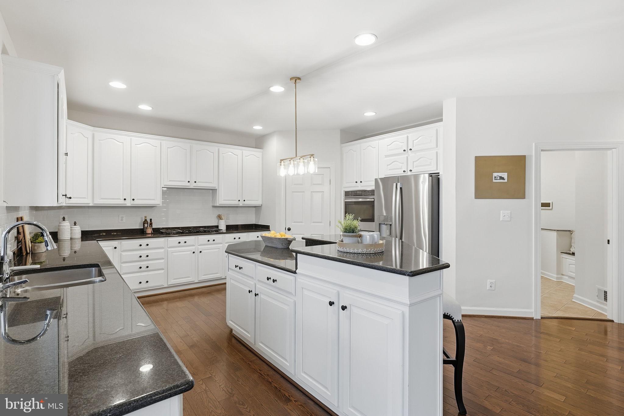 11588 Cedar Chase Road Herndon, VA 20170 - Photo 38 of 81 a kitchen with stainless steel appliances kitchen island granite countertop a stove a sink a refrigerator and white cabinets with wooden floor
