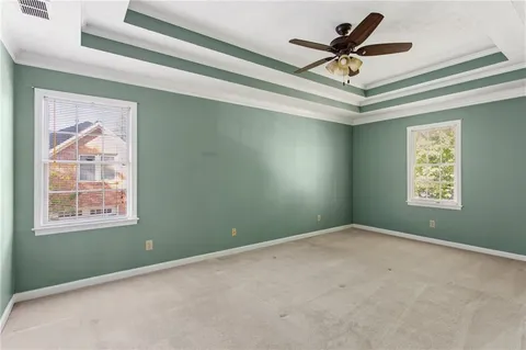 an empty room with ceiling fan and windows