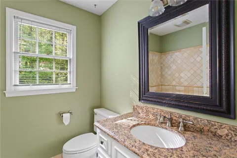 a bathroom with a granite countertop toilet sink and mirror