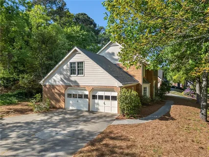 a view of a house with a yard and large trees