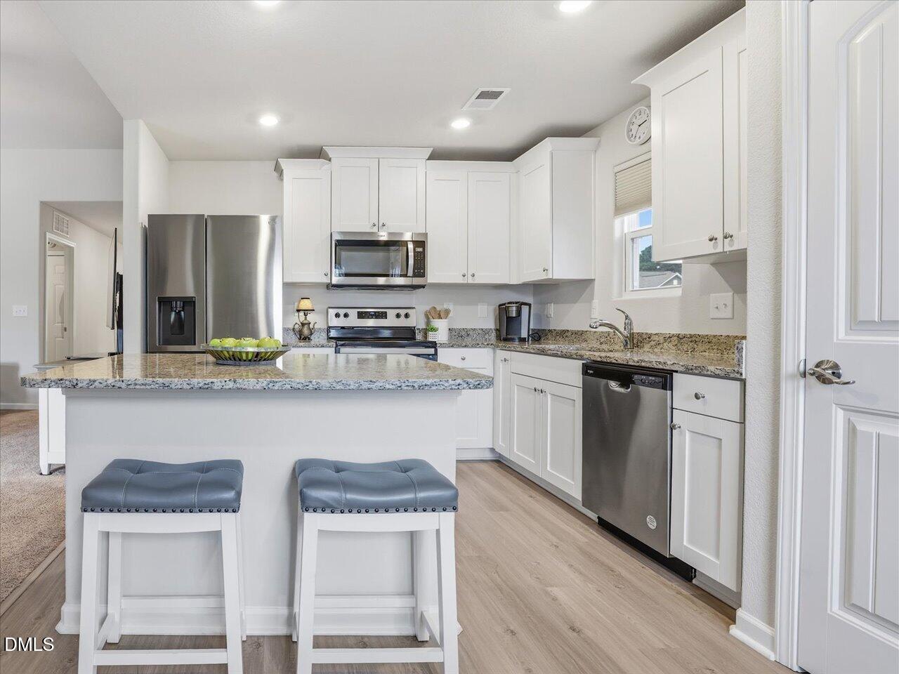 90 Barnsley Road Angier, NC 27501 - Photo 16 of 40 a kitchen with stainless steel appliances granite countertop a white cabinets and wooden floor