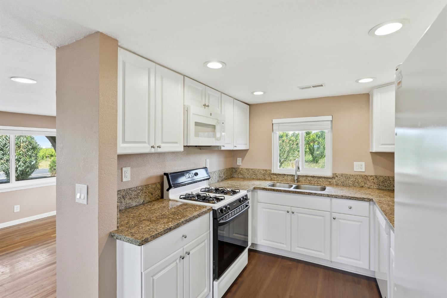 20042 North Ray Road Lodi, CA 95242 - Photo 19 of 63 a kitchen with granite countertop white cabinets and white appliances