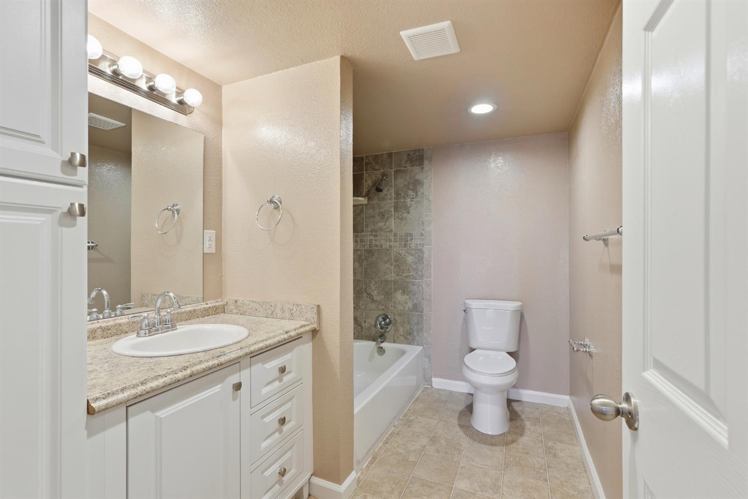 20042 North Ray Road Lodi, CA 95242 - Photo 29 of 63 a bathroom with a granite countertop sink a toilet a mirror and shower