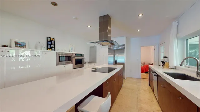 a kitchen with stainless steel appliances a sink dishwasher a stove a dining table and chairs with wooden floor