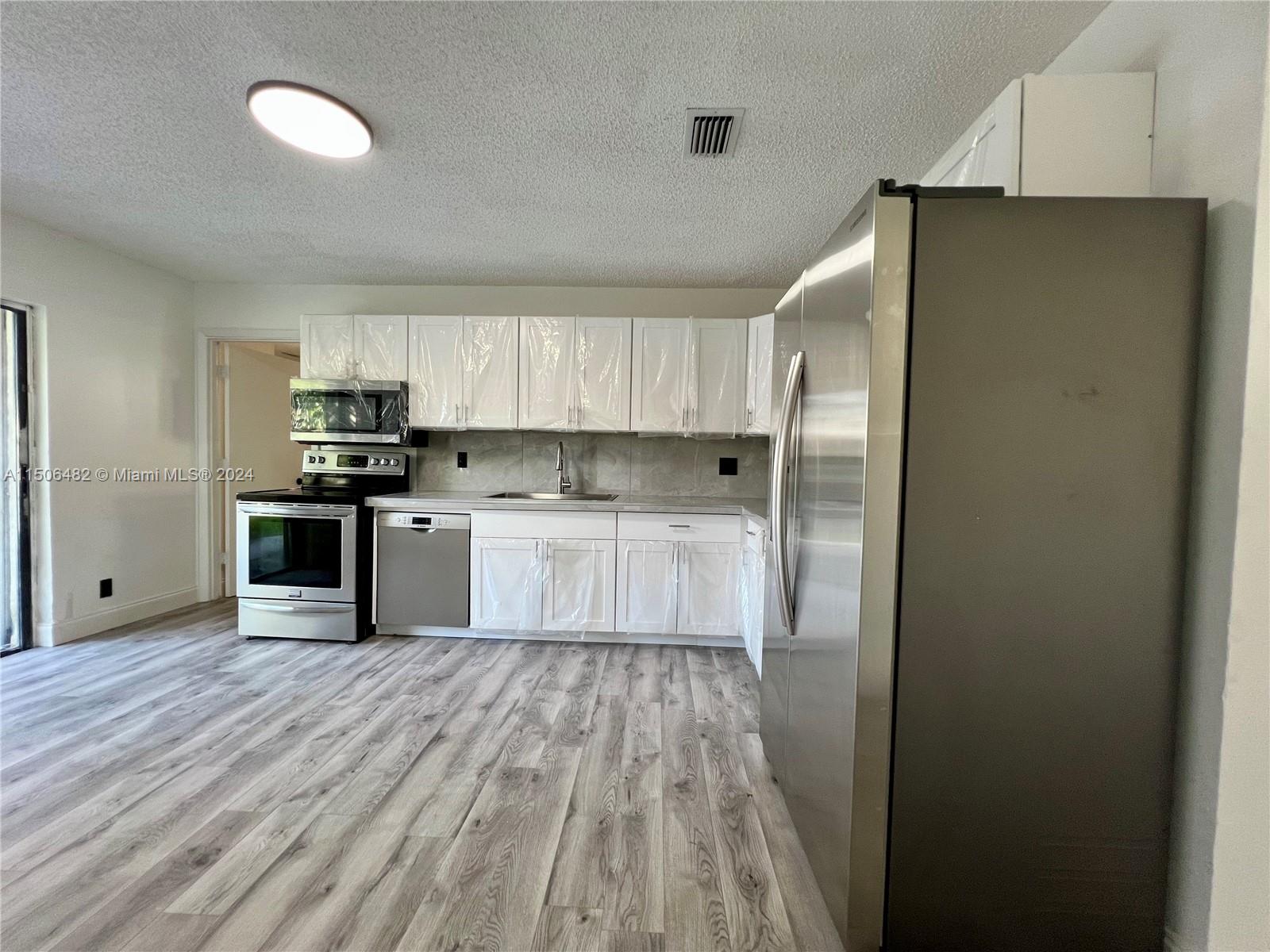 6034 Triphammer Road Lake Worth, FL 33463 - Photo 2 of 10 a kitchen with wooden cabinets and stainless steel appliances
