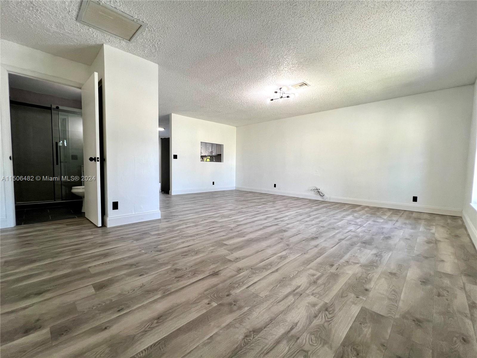 6034 Triphammer Road Lake Worth, FL 33463 - Photo 3 of 10 an empty room with wooden floor and bathroom