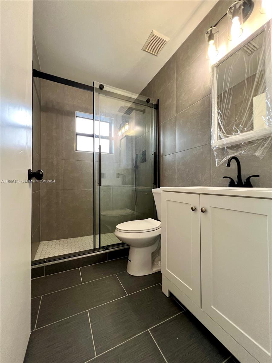 6034 Triphammer Road Lake Worth, FL 33463 - Photo 8 of 10 a bathroom with a toilet a sink and glass door