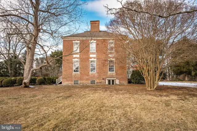 a view of a large white house with a yard with a tree