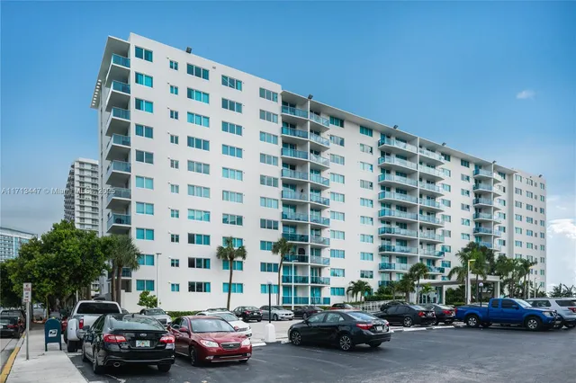 a front view of multi story residential apartment building with yard and green space