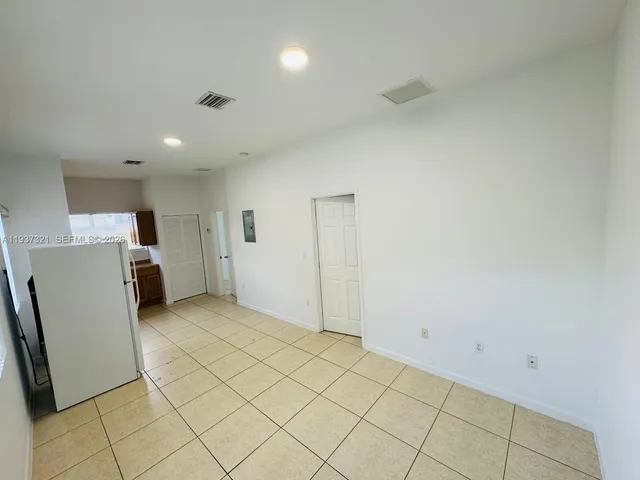 a view of a kitchen with refrigerator and white cabinets