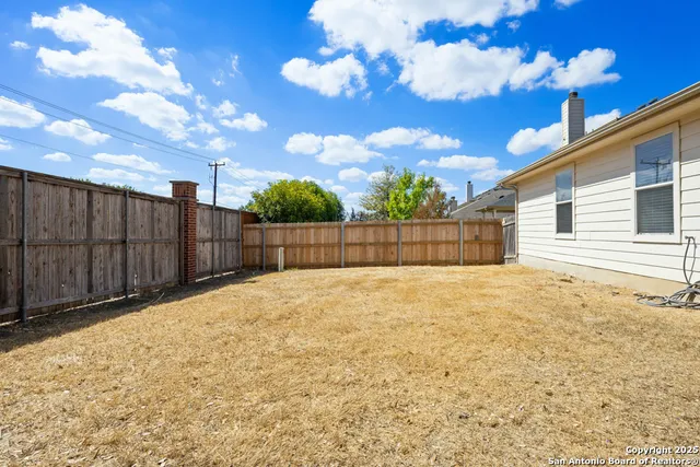a view of backyard with wooden fence