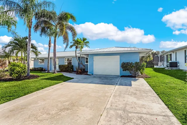 a view of a house with a yard and coconut trees