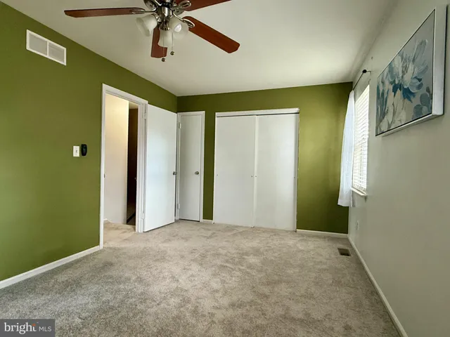 a view of a hallway with closet and chandelier fan
