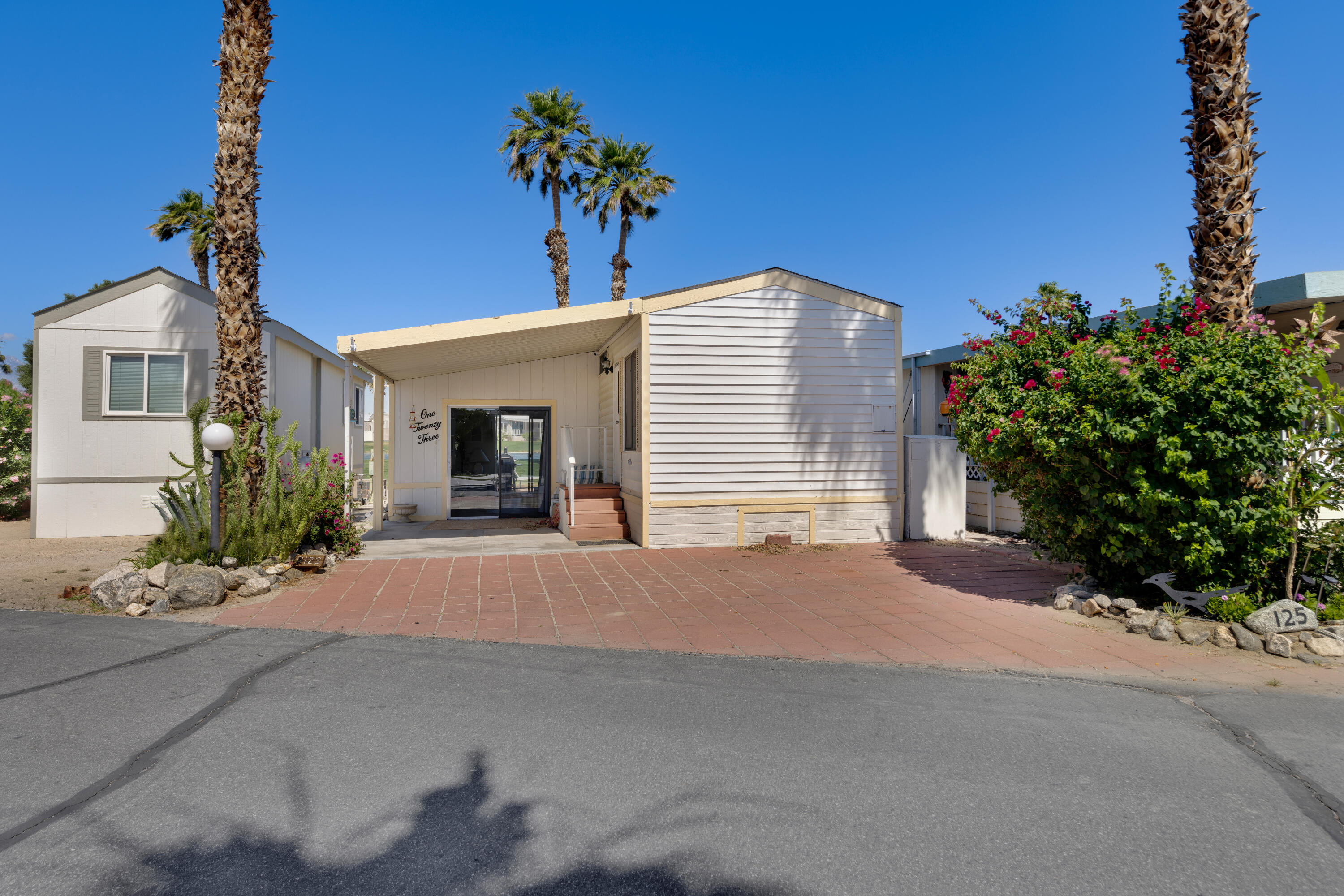 74711 Dillon Road, Unit 123 Sky Valley, CA 92241 - Photo 1 of 23 a front view of a house with a yard and a garage